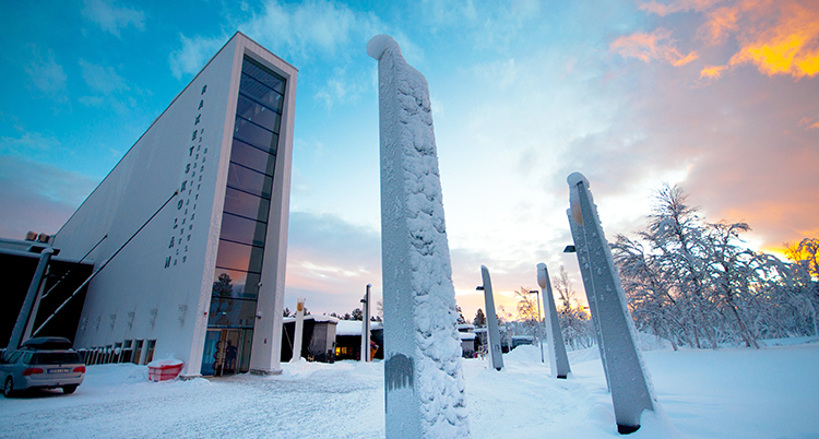 Det är snöigt utanför ingången till skolan. Några stolpar syns närmast i bild.