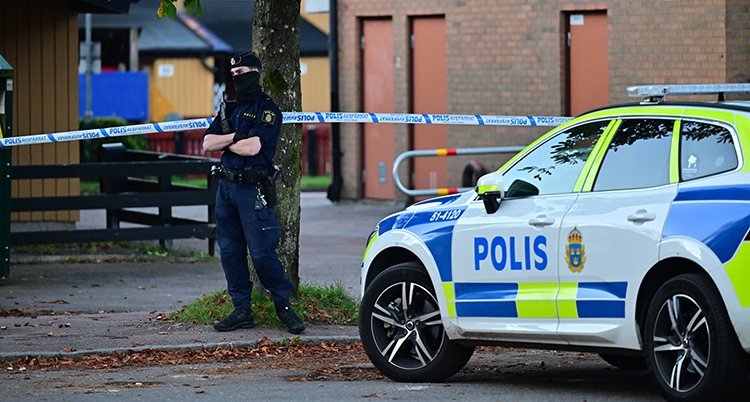 En polisbil och en polis syns. Tejp har spärrat av platsen.