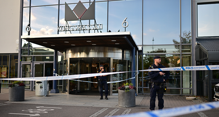 Poliser står utanför gallerian. Det är polisband som stänger vägen.