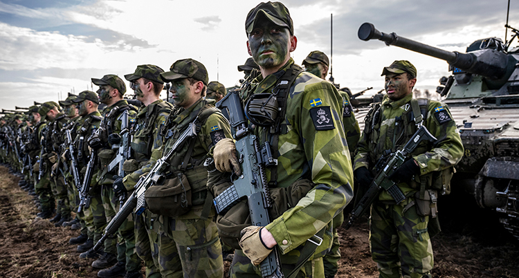 Militärer i gröna kläder och svarta ansikten står på rad.