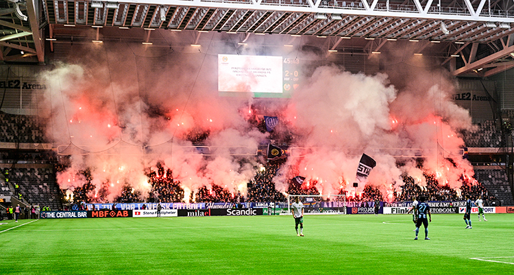 En arena för fotboll. Det ryker och brinner på läktarna.