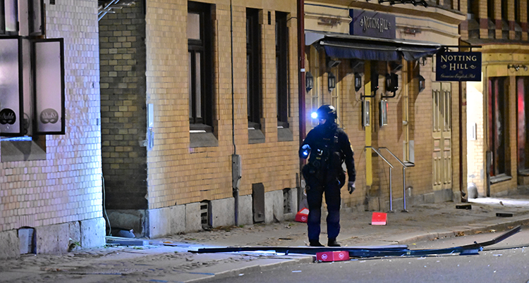 En polis jobbar utanför porten som exploderade. Det ligger bråte på marken.