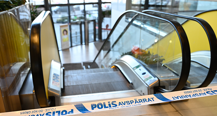 Inne i en galleria. Poliserna har satt upp ett band vid en rulltrappa.