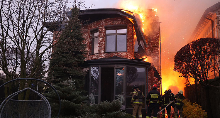 Brandmännen jobbar med att släcka en eld vid ett hus.