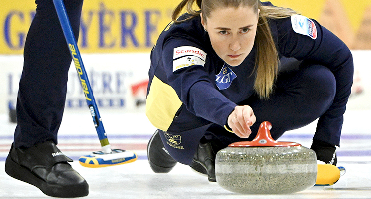 Från en match i curling. En kvinna skjuter iväg en sten på isen.