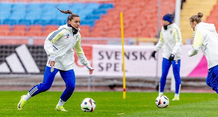 Hon håller på med en fotboll på en fotbollsplan.