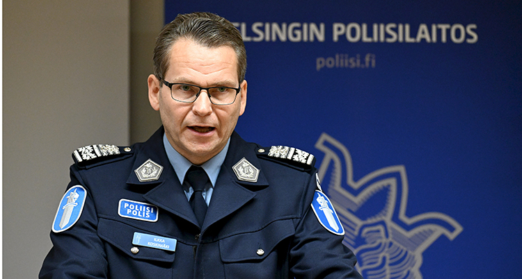 Han pratar i en mikrofon. Han har Finlands uniform för poliser på sig.