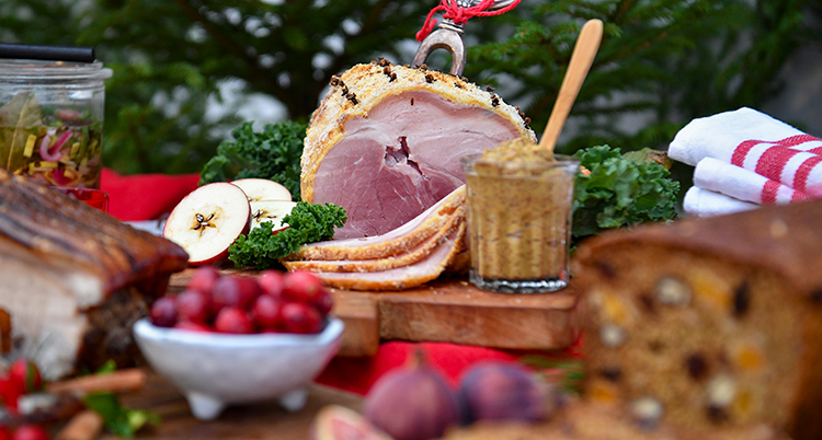 Många olika rätter står uppdukade på ett bord. En skinka med en gaffel i syns tydligt.