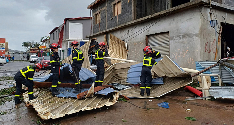 Flera brandmäm jobbar vid ett förstört hus.