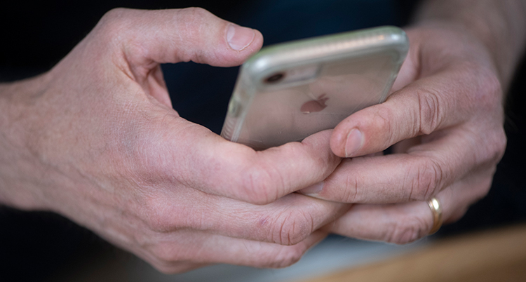 En person håller i en telefon. Bara personens händer syns.