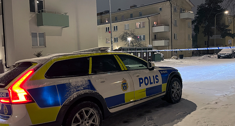 En polisbil står parkerade utanför ett hus.