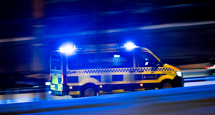 En ambulans med blå sirener kör iväg.