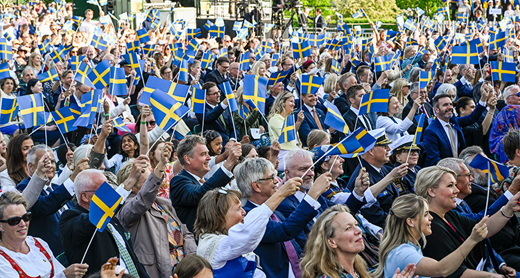 Massor av människor på Skansen viftar med svenska flaggor.