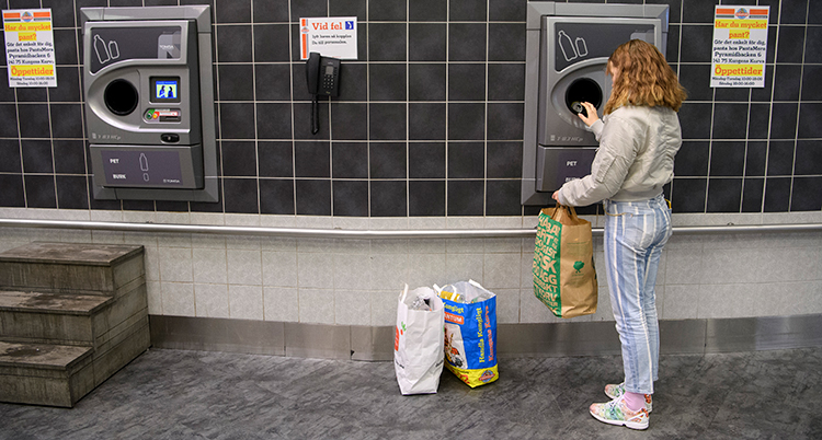 En tjej pantar burkar i en automat.