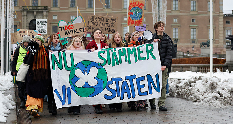 Unga personer håller i en stor skylt där det står Nu stämmer vi staten.