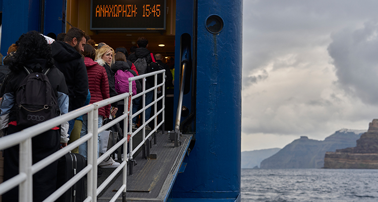 Folk går på en färja. Bakom syns havet och öar.