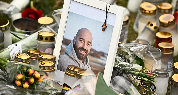 Ett inramat foto på Salim Iskef mitt i havet av ljus och blommor för dem som dött. Salim ler på bilden och tittar in i kameran. På fotot hänger ett litet kors i en kedja.