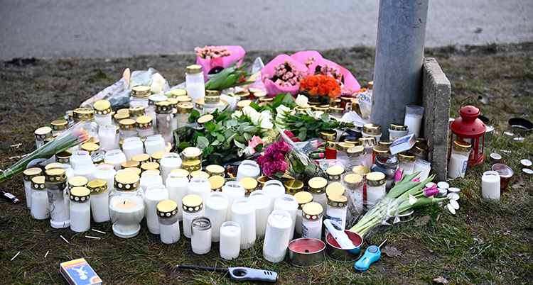 Blommor och ljus på marken nära skolan.