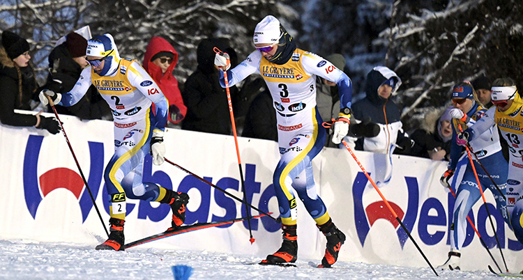 De åker skidor uppför en backe under en tävling.