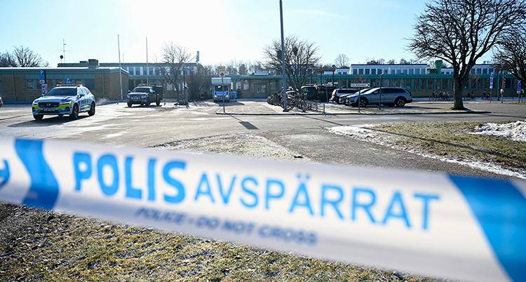 Polisernas tejp syns nära. Bakom syns skolan och flera polisbilar.