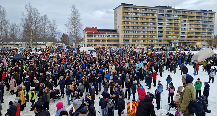 Många personer står framför ett högt hus.