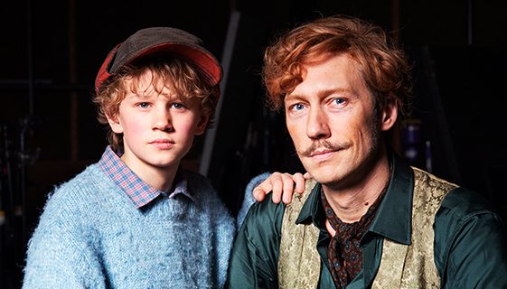 De är bredvid varandra. De tittar in i kameran.