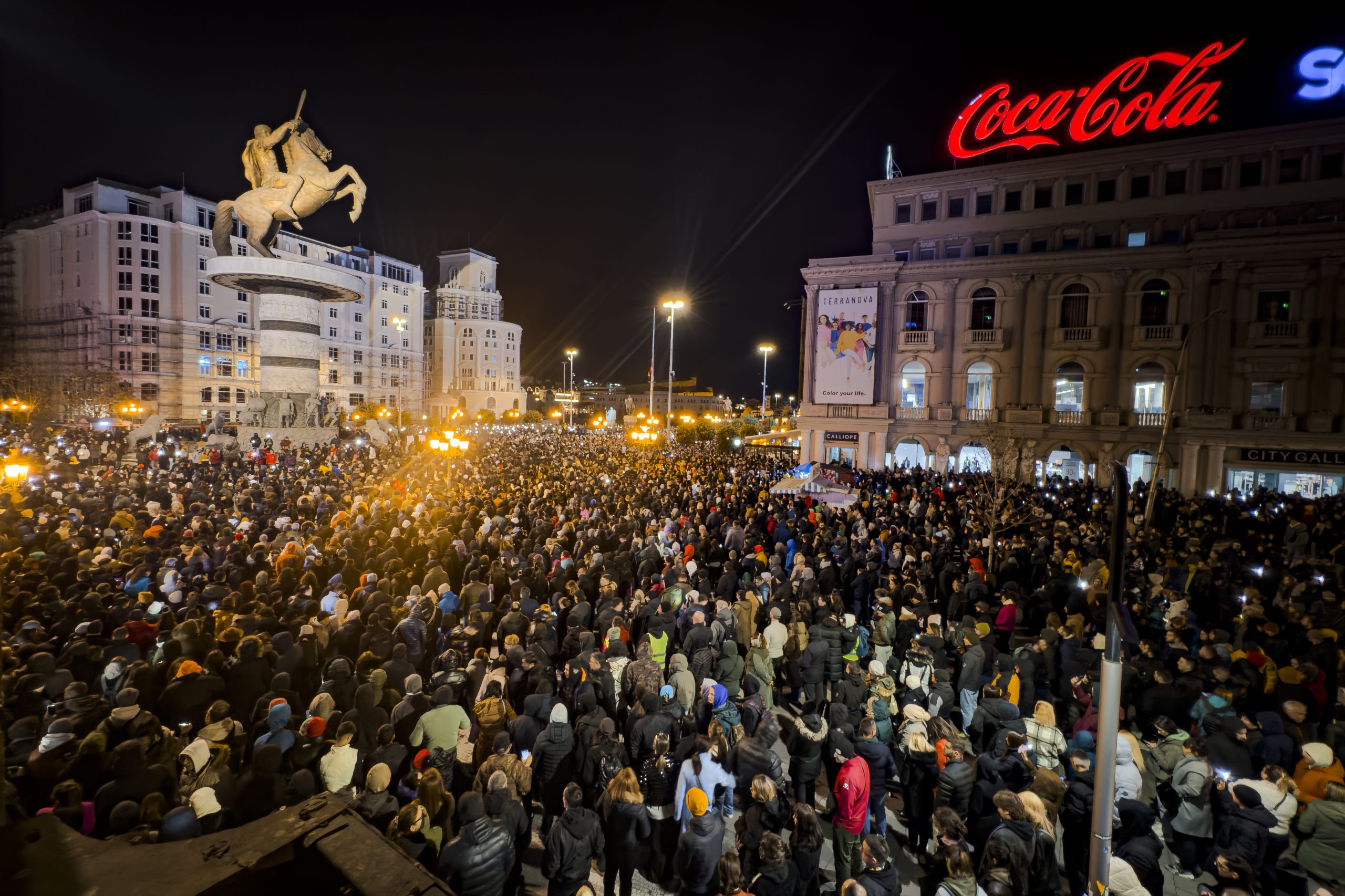 Många människor står på ett stort torg i en stad.