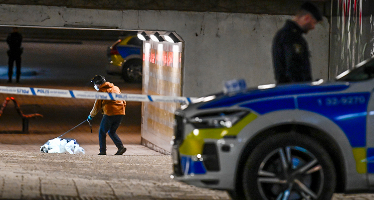 En avspärrad plats där en person plockar upp något från marken.