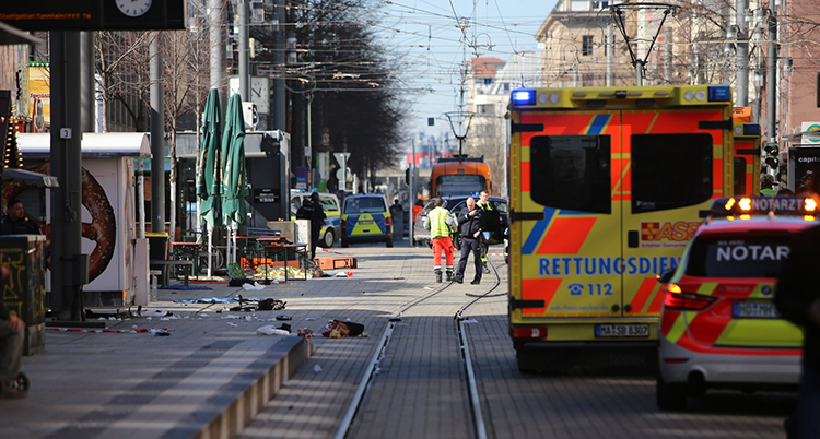 Bilar står på gatan. Personer i gula västar jobbar på gatan.