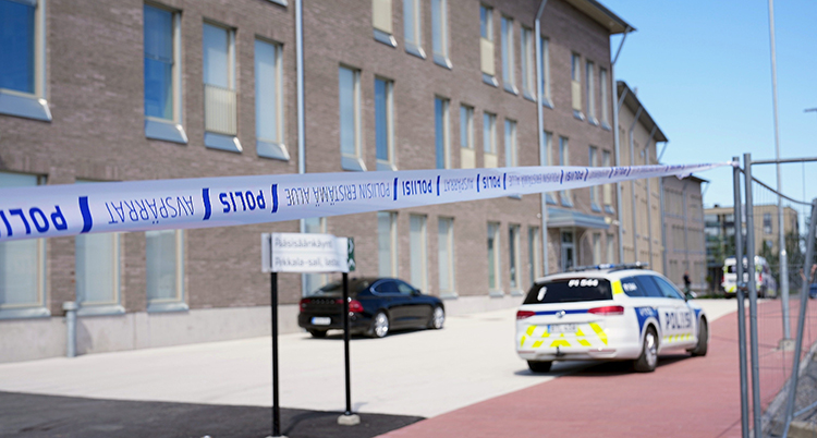 Tejp har spärrat av en gata. En polisbil står på gatan.