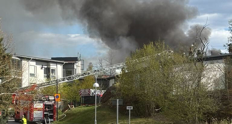 En brandbil står utanför huset. Det röker mycket från taket.