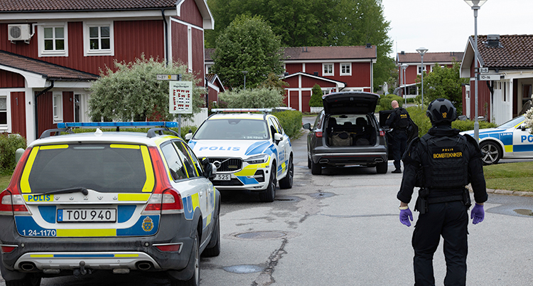 Polisbilar står på en väg. Poliser syns. Det är flera tvåplanshus i området.