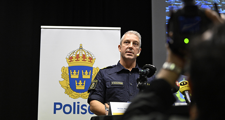 Han står framför en skylt med en bild på polisernas märke.