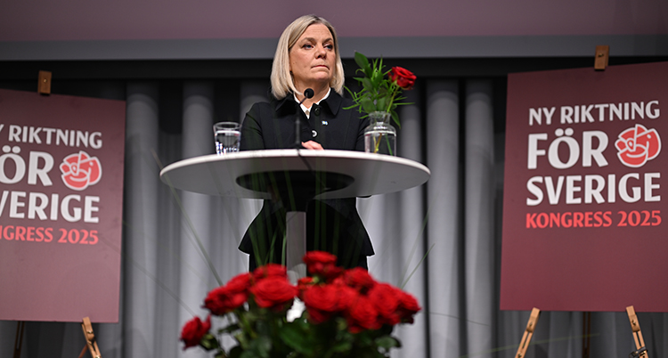 Magdalena Andersson står på en scen vid ett bord. Framför henne finns massor av röda rosor.
