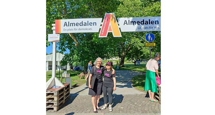 De står bredvid varandra under en skylt. På skylten står det Almedalen.