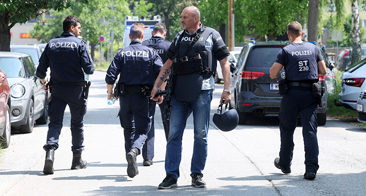 Några poliser i uniform är på väg bort. En man står rakt fram med en hjälm i handen.