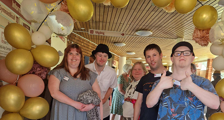 De står bredvid varandra under en båge med ballonger.