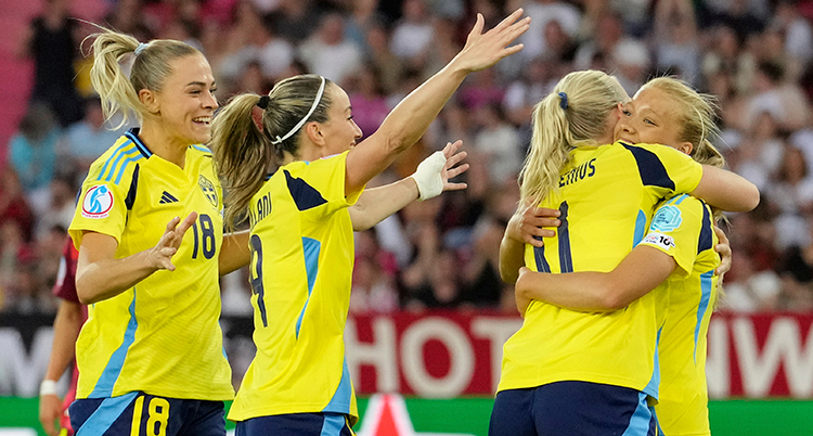 Flera glada spelare kramar varandra och sträcker upp armarna.