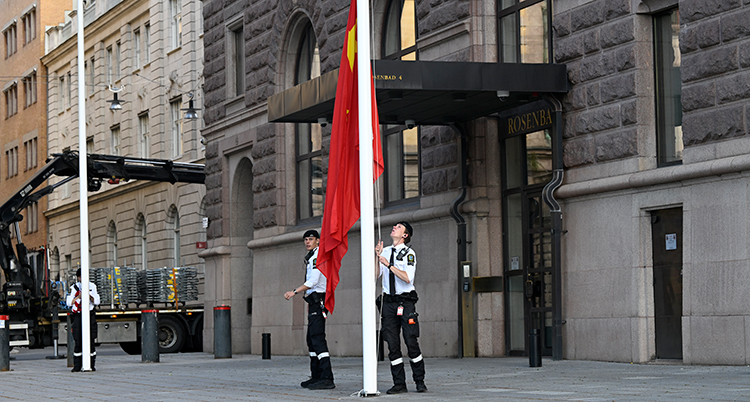 Två vakter jobbar med att hissa en flagga.