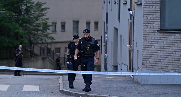 Poliser går på en avspärrad gata.