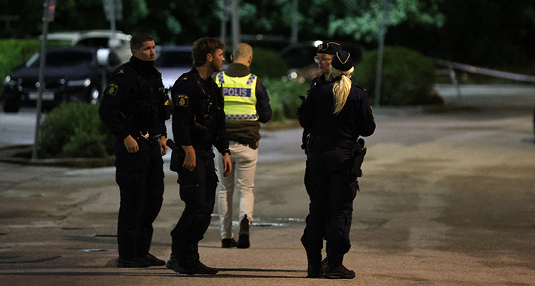 Det är mörkt. Flera poliser står på en gata.