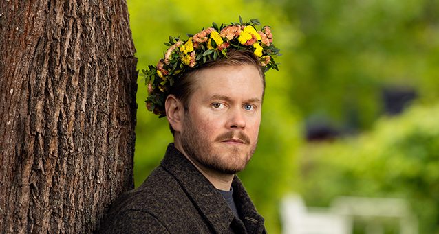 Han har en krans med blommor på huvudet.