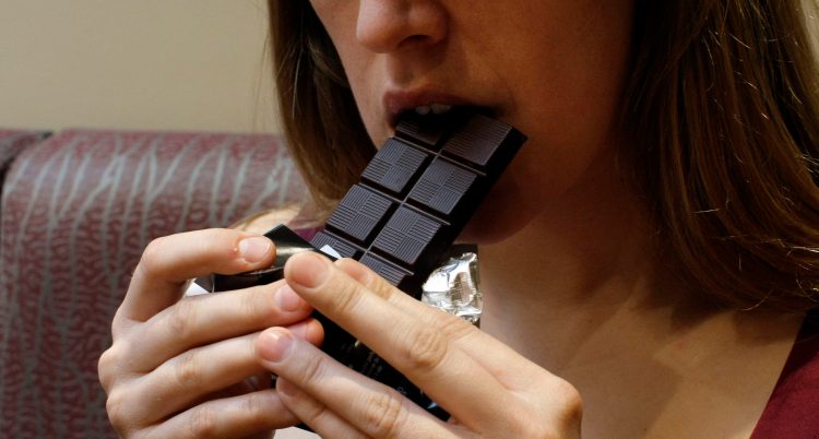 En kvinna tar en tugga på en chokladkaka.