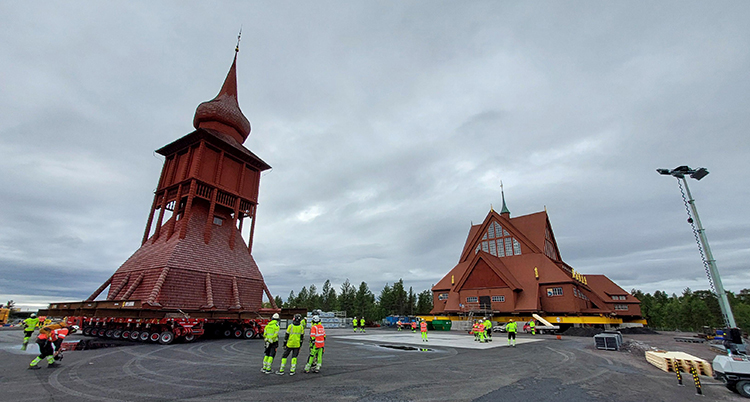 En kyrka och ett klocktorn. Några arbetare står framför.