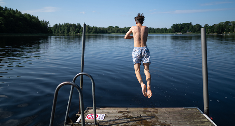 Han hoppar i vattnet från en brygga.