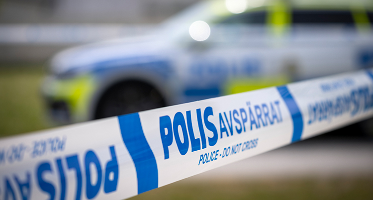 Ett band av plast som det står polis på. Bakom syns en polisbil.
