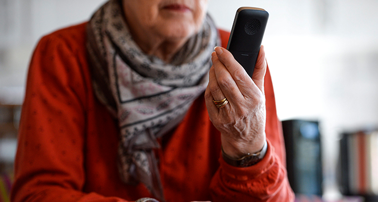 En gammal person håller i en telefon.