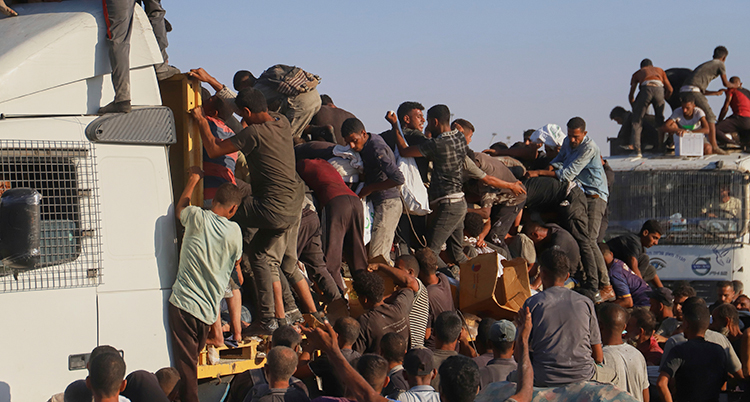 Människor klättrar på lastbilar med saker som ska hjälpa människorna i Gaza.