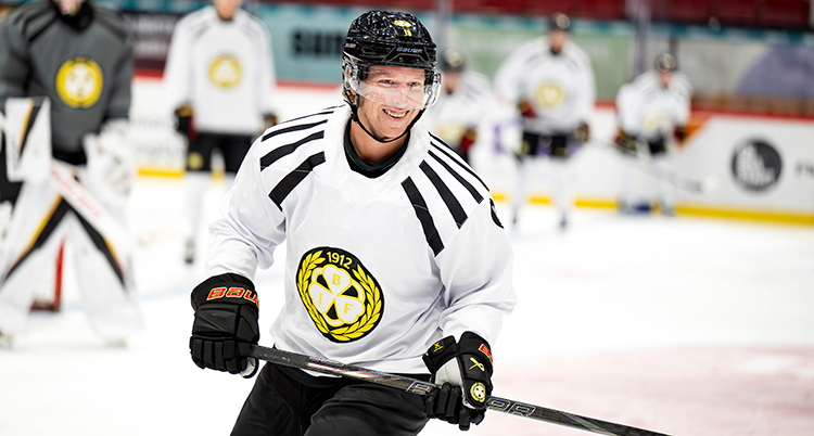 Han åker skridsko på isen och har på sig hockeygrejer. Han ser glad ut.