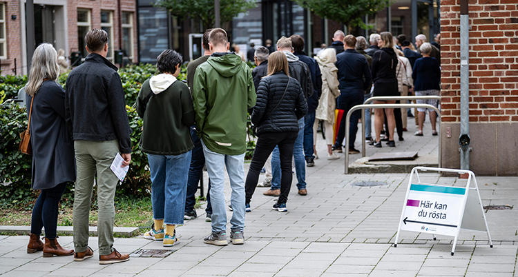Folk står i en kö utanför en skola i Malmö. De ska in och rösta.